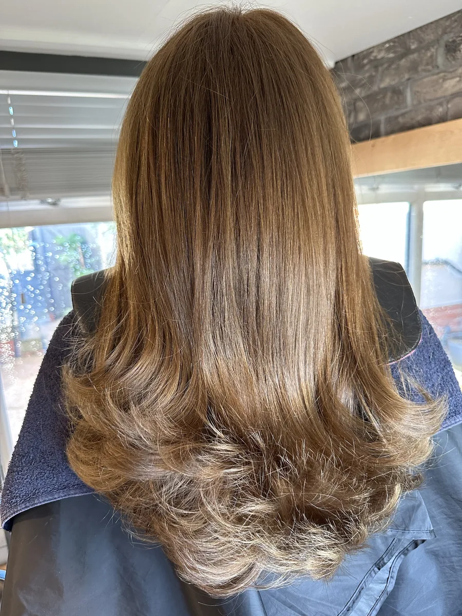 Glossy brown hair with a flicked, layered blow-dry