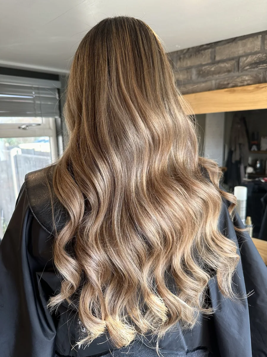 After: long, dry brown hair refreshed to honey balayage with soft waves