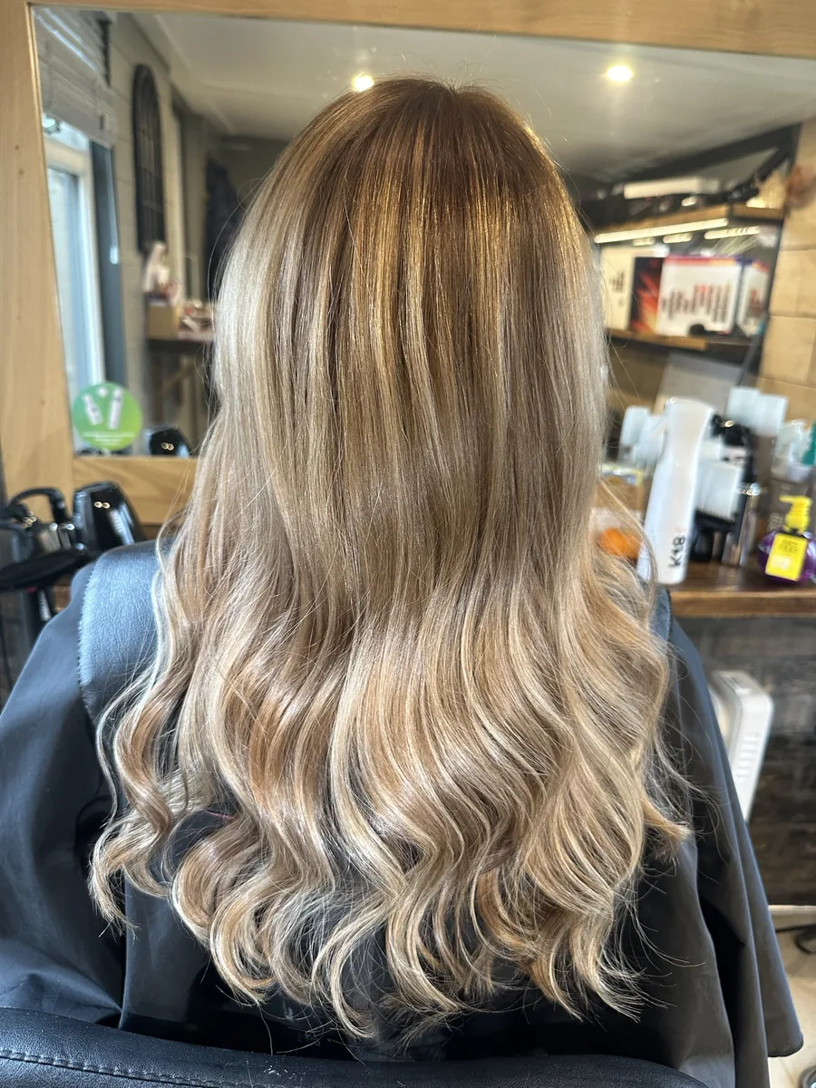 After: long, dry platinum blonde with dark roots changed to warm honey blonde waves